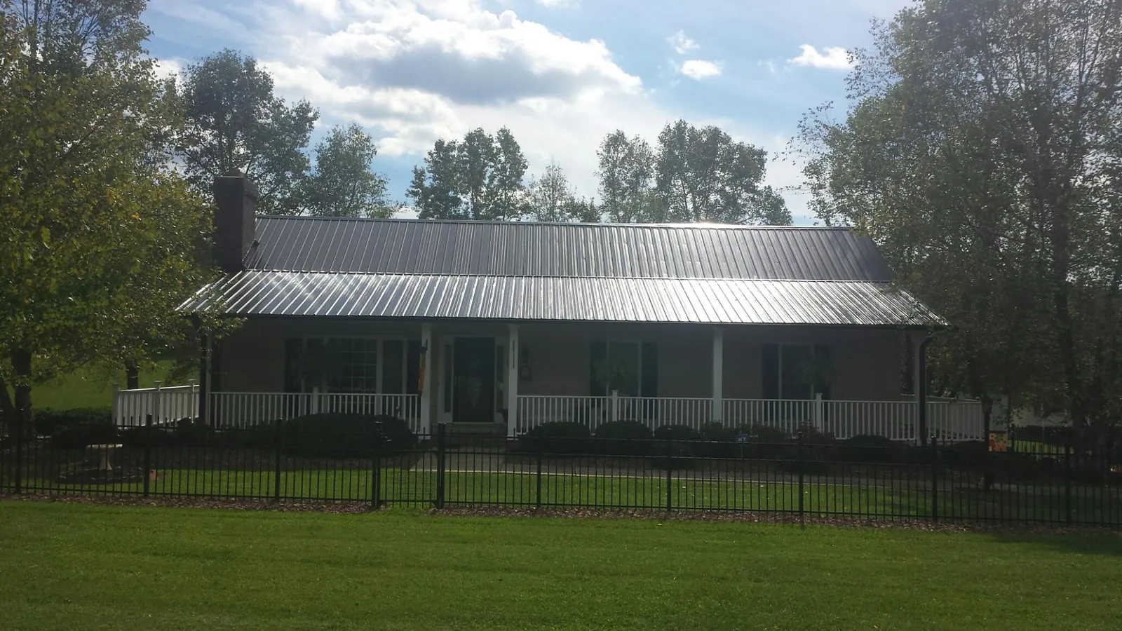 Gray metal roof on a brick ranch with a full width front porch — Gutter Guard Installation work by our crew in Fort Myers