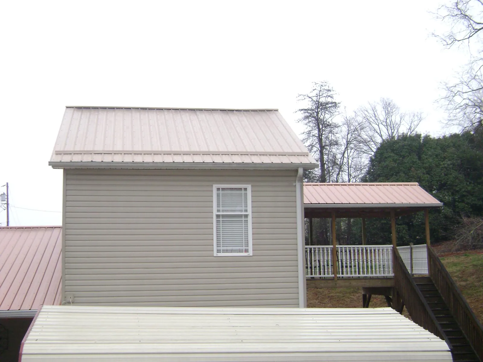 Tan metal roofs on a two story addition and attached porch, from a Roof Replacement job in Fort Myers