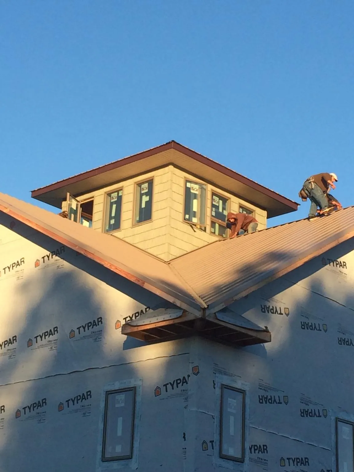 Roofers working around a rooftop cupola on a new metal roof at sunset — Roof Waterproofing in Fort Myers by Roofing Brothers